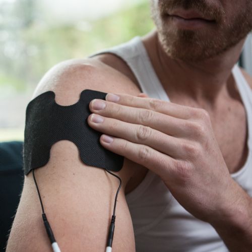 Large iReliev TENS EMS Pad shown in use on the shoulder to reduce muscle aches and pain.