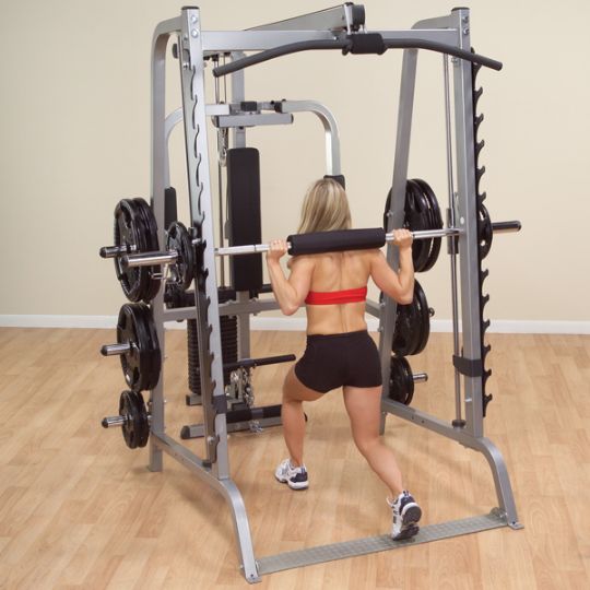 The user performing lunges while utilizing the weight bar and round weights of the Body-Solid Series 7 Smith Gym System