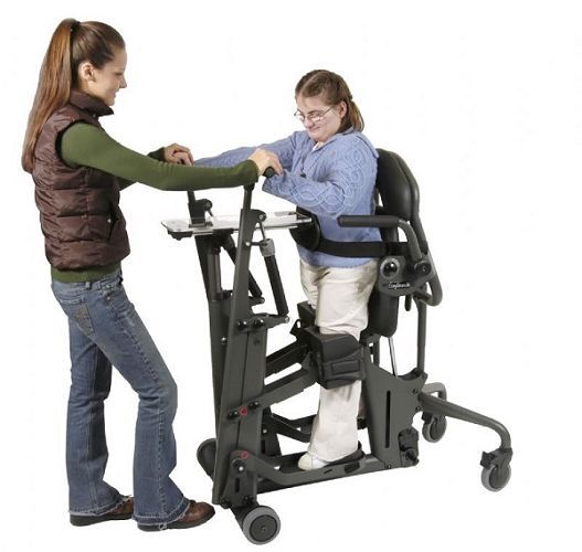 EasyStand Glider in use with caregiver supervision - shows optional Removable Contoured Back Support