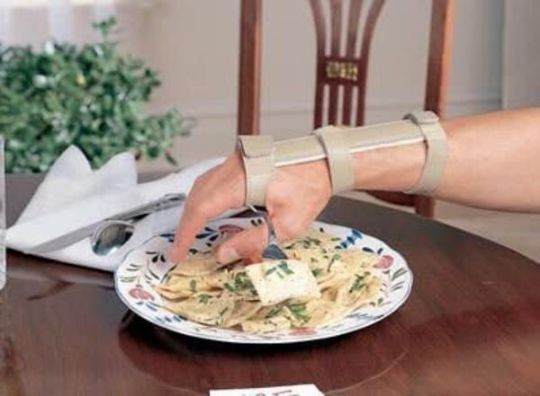 Economy Dorsal Wrist Support with Universal Cuff shown using fork utensil