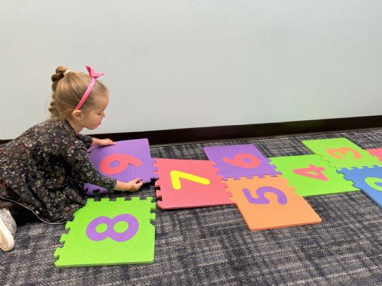 Child assembling colorful interlocking foam tiles with numbers for fun and educational play