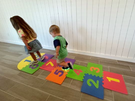 Two children enjoying a fun game of hopscotch on vibrant foam number tiles