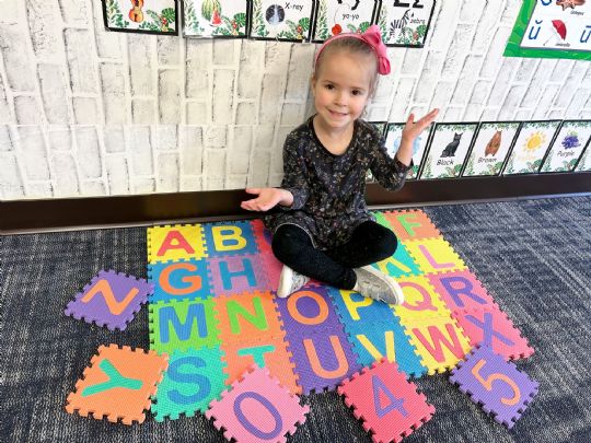 Smiling child playing with colorful alphabet foam tiles for fun learning