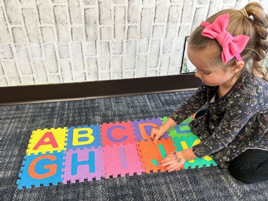 Child arranging colorful alphabet foam tiles for interactive learning and play