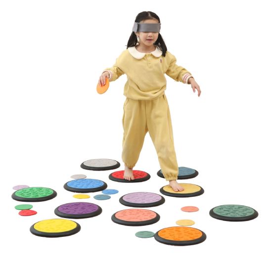 Child exploring tactile game tiles while wearing a blindfold for sensory play