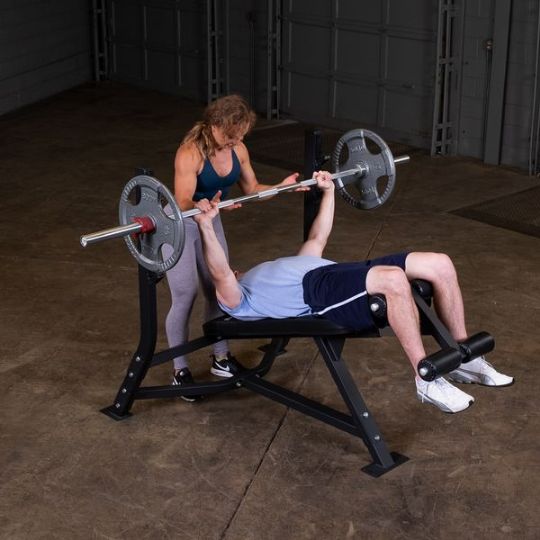 Executing bench barbell press with spotter (barbell and weights not included)