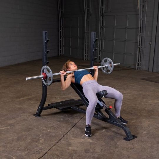 Executing incline barbell press with medium weights (barbell and weights not included)