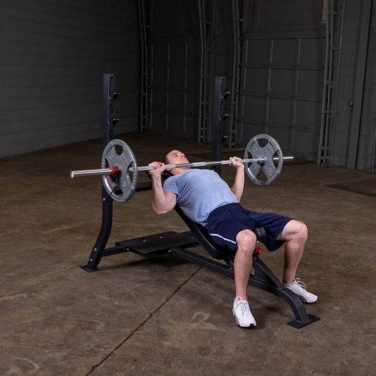 Executing incline barbell press with larger weights (barbell and weights not included)