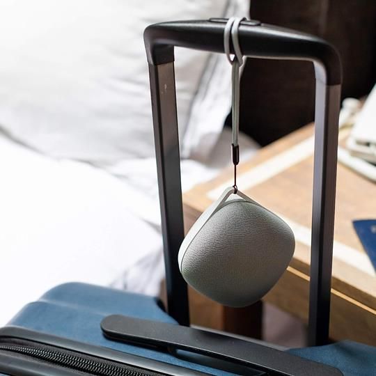 Yogasleep Travelcube white noise machine conveniently attached to luggage for easy travel