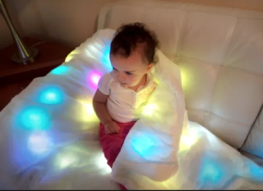 Child using the LED Multi-Sensory Light-Up Blanket 