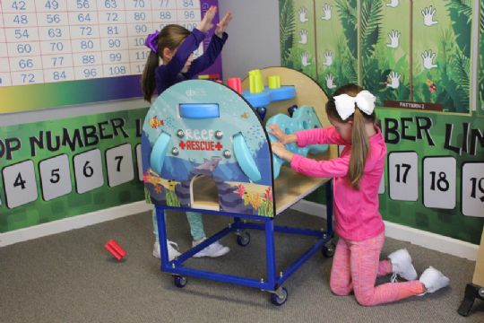 Children collaborating and celebrating while engaging with the Reef Rescue activity center